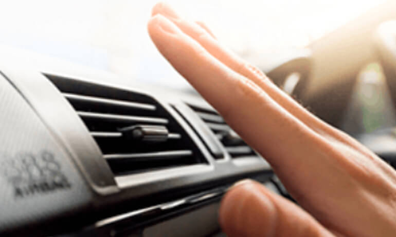 Mão sobre a saída de ar-condicionado do carro.