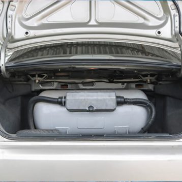 Carro sedã prata com cilindro de GNV cinza no porta malas